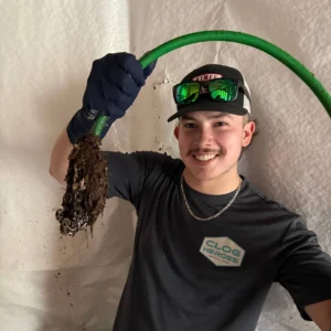 Clog Heroes technician holding green hose with debris after snaking a clogged drain in Stafford VA
