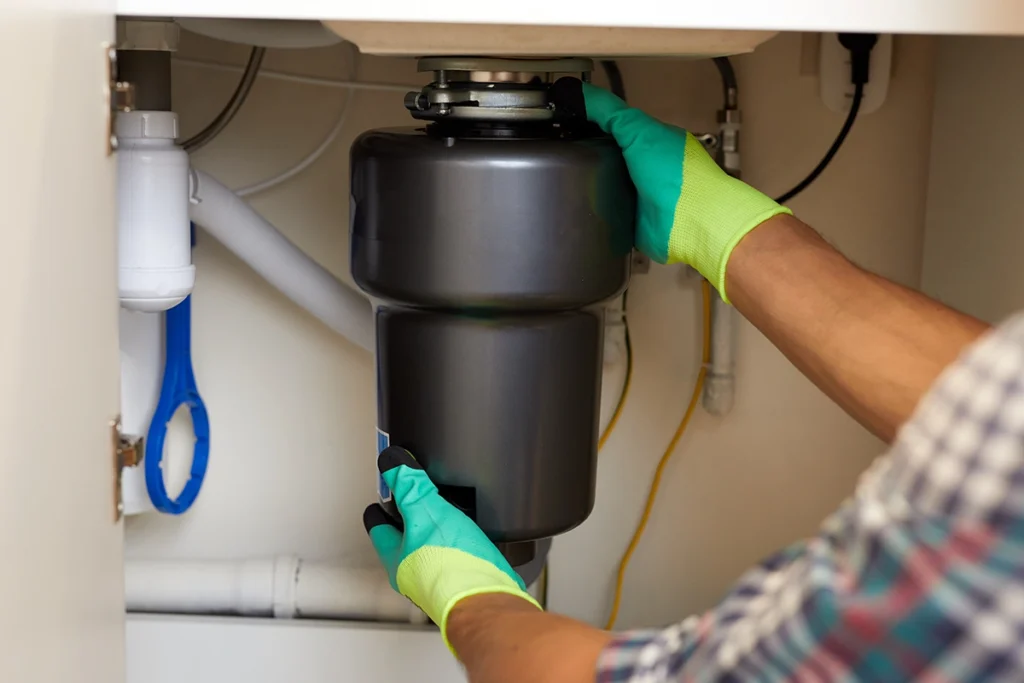 Technician inspecting garbage disposal humming but not working under kitchen sink