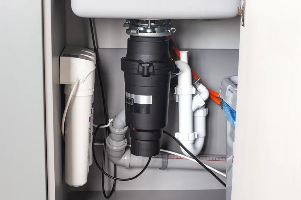 garbage disposal under kitchen sink connected to P-trap and drain piping showing common area where garbage disposal smells originate