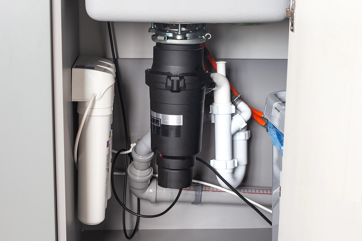 garbage disposal under kitchen sink connected to P-trap and drain piping showing common area where garbage disposal smells originate