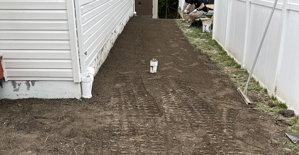 Outdoor sewer cleanout cap in a side yard next to a home