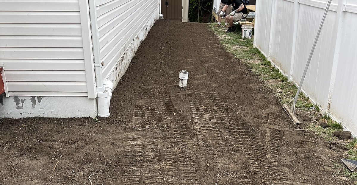 Outdoor sewer cleanout cap in a side yard next to a home