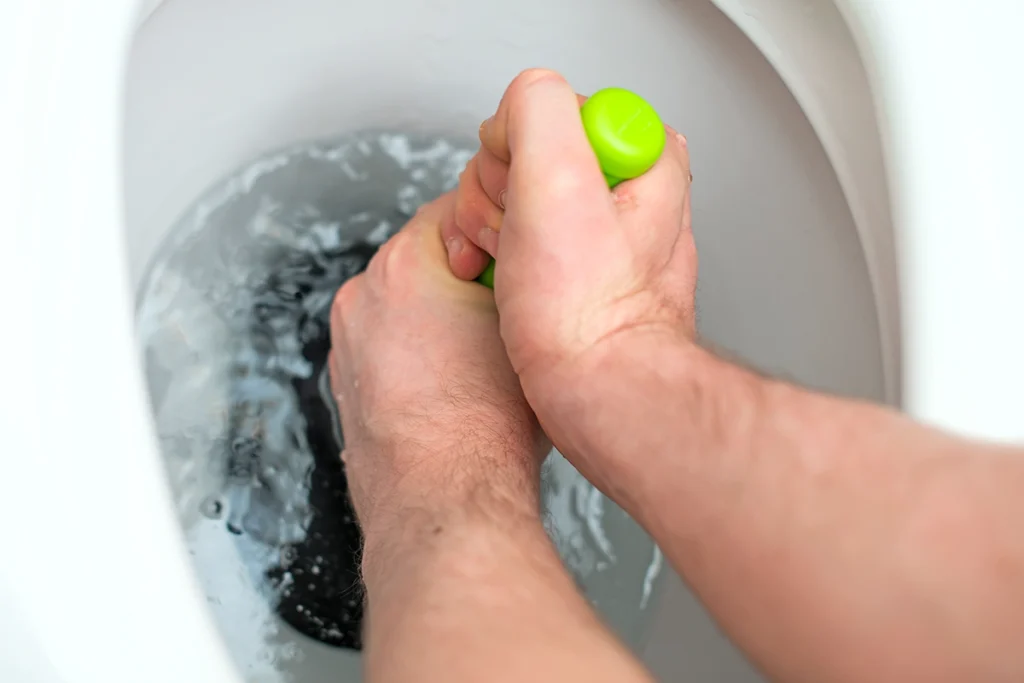 plunging a clogged toilet bowl to stop a toilet overflowing