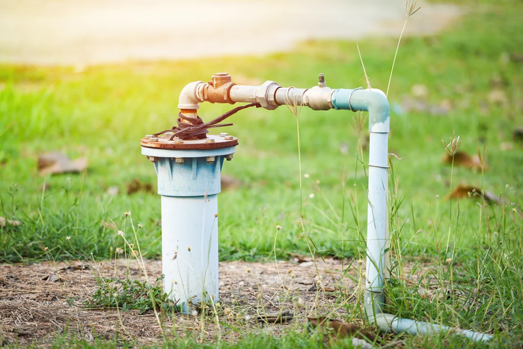 How does well water work with a residential well head and above-ground piping in a grassy yard