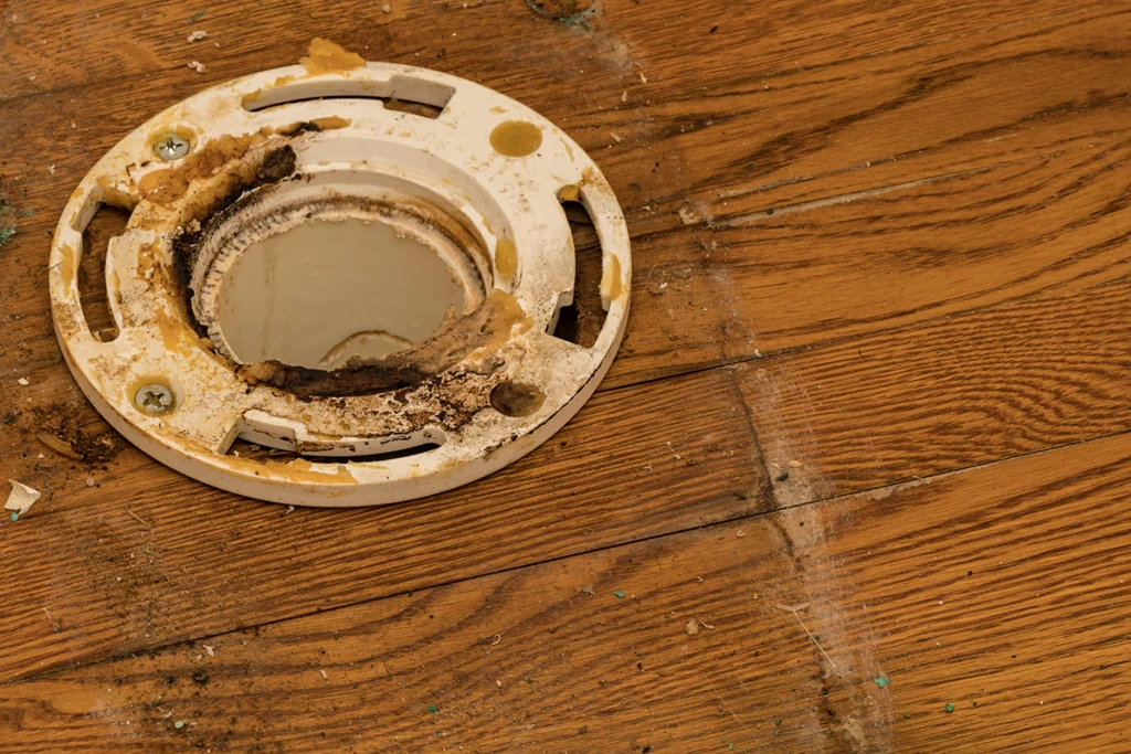 damaged PVC toilet flange on bathroom floor
